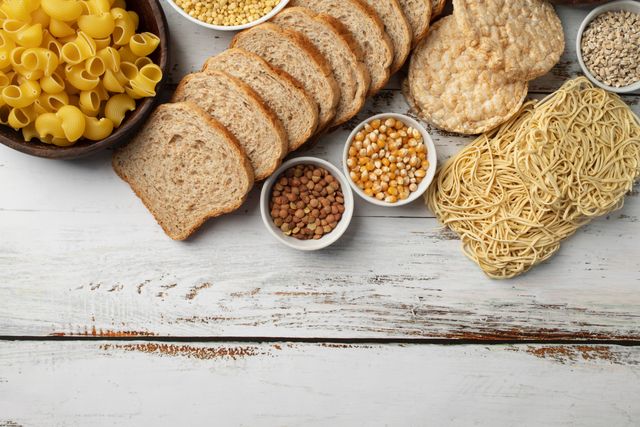Glutenhaltige Lebensmittel wie Brot, Pasta und Getreide auf einem Holztisch – Thema Glutenintoleranz bei Kindern in der Kinderarztpraxis Chur West