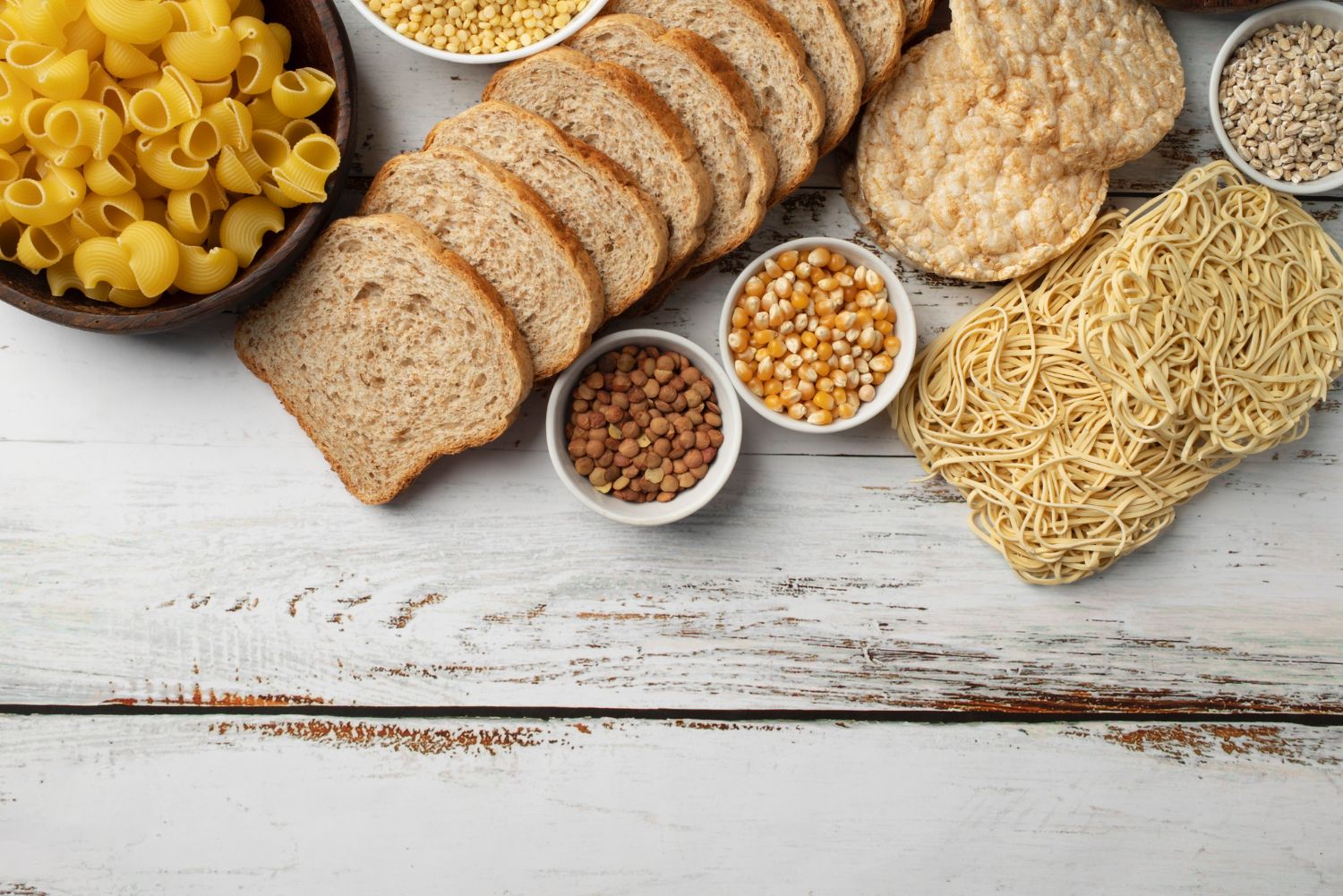 Glutenhaltige Lebensmittel wie Brot, Pasta und Getreide auf einem Holztisch – Thema Glutenintoleranz bei Kindern in der Kinderarztpraxis Chur West