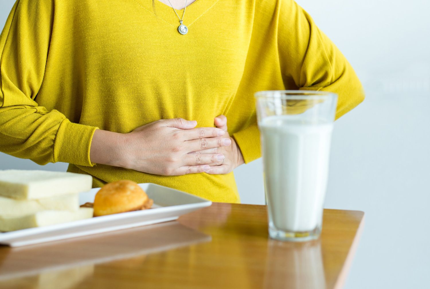 Kind mit Bauchschmerzen neben einem Glas Milch – typische Beschwerden bei Laktoseintoleranz, Abklärung in der Kinderarztpraxis Chur West