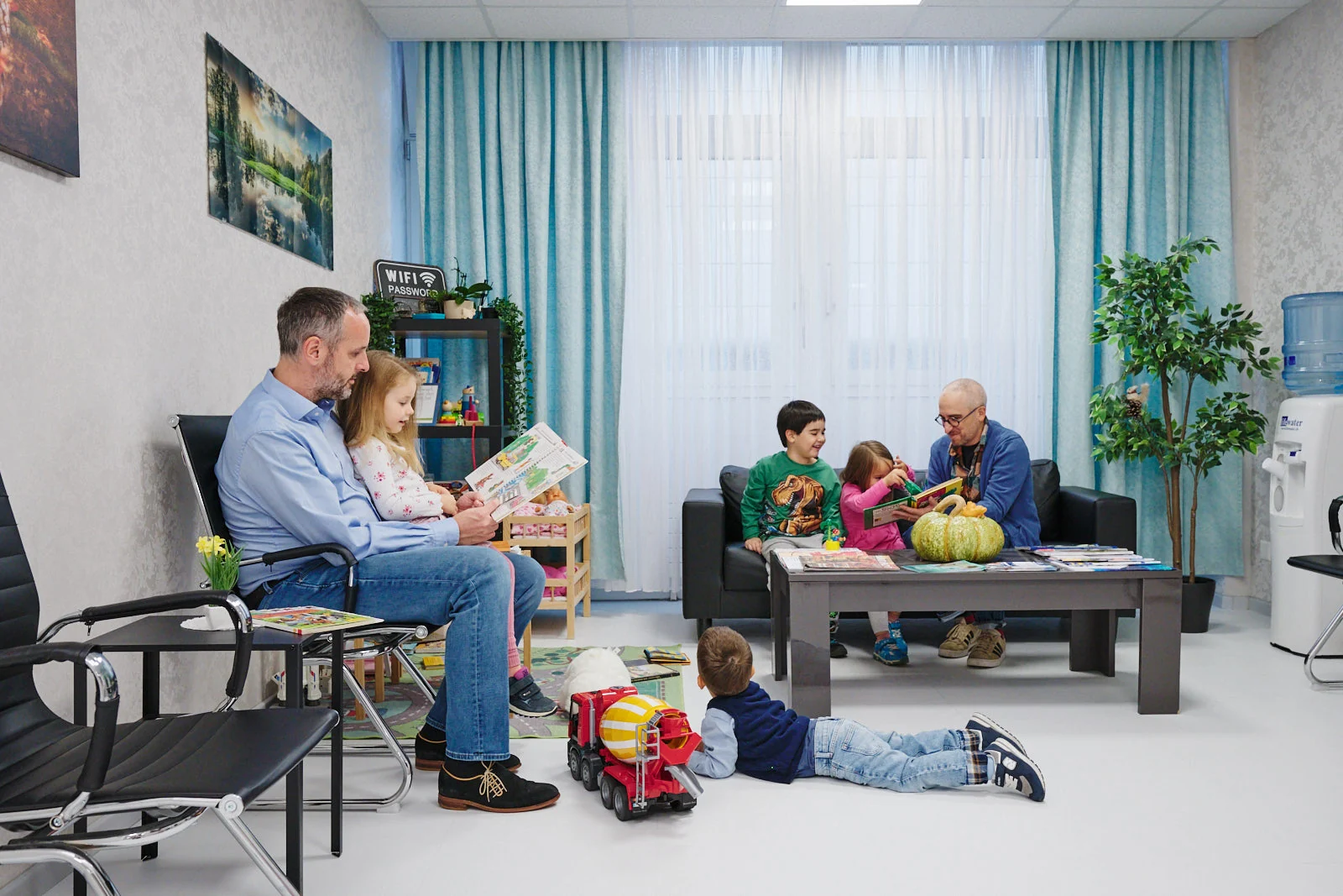 Eltern lesen ihren Kindern im Wartezimmer der Kinderarztpraxis Chur West vor – familienfreundliche Pädiatrische Praxis Chur